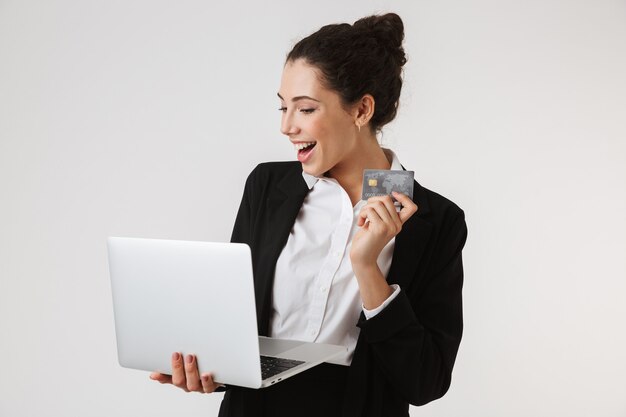 Sourire jeune femme d'affaires utilisant un ordinateur portable tenant une carte de crédit.