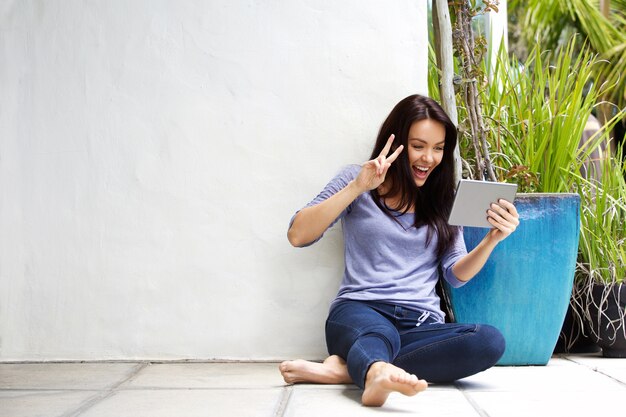 Sourire jeune femme faisant un appel vidéo en utilisant une tablette numérique