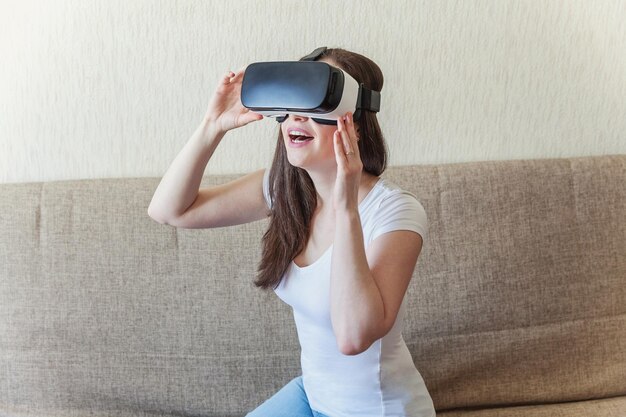 Sourire jeune femme portant à l'aide d'un casque de casque de lunettes de réalité virtuelle vr à la maison