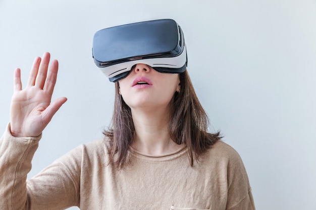 Sourire jeune femme portant des lunettes de réalité virtuelle VR casque casque sur fond blanc.