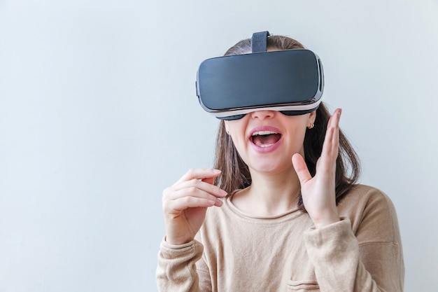 Sourire jeune femme portant des lunettes de réalité virtuelle VR casque casque sur fond blanc.