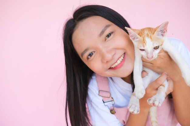 Sourire jeune fille avec chat sur fond rose