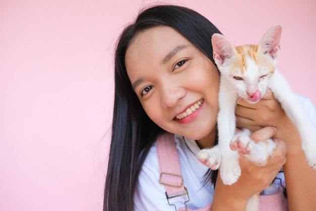 Sourire jeune fille avec chat sur fond rose