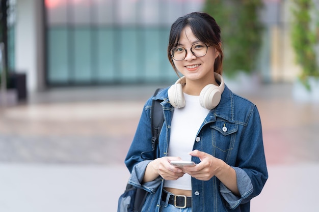 Sourire de jeune fille en regardant et en utilisant des écouteurs de téléphone portable