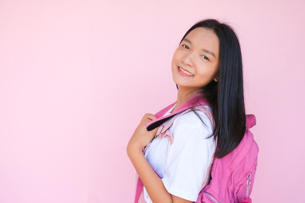 Sourire jeune fille avec sac à dos sur fond rose