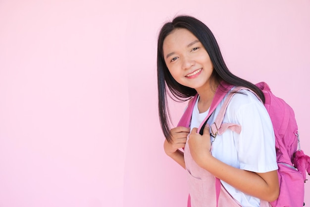 Sourire jeune fille avec sac à dos sur fond rose