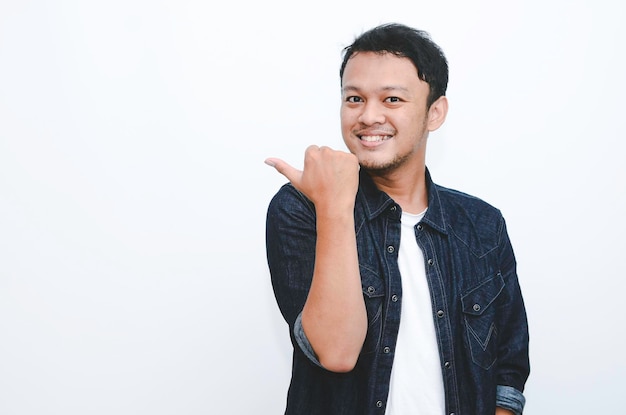 Sourire de jeune homme asiatique en chemise blanche avec point de main sur l'espace vide