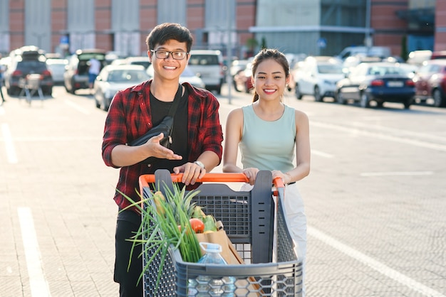 Sourire, jeune, vietnamien, garçon fille, porter, marché, chariot, à, différent, nourriture, près, supermarché