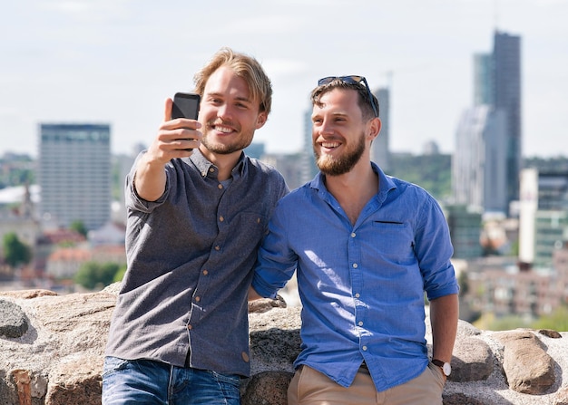 Sourire de jeunes amis caucasiens faisant selfie devant les toits de la ville comme concept de voyage et d'amitié