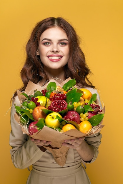 Sourire de jolie femme posant des émotions de bouquet de fruits frais fond isolé