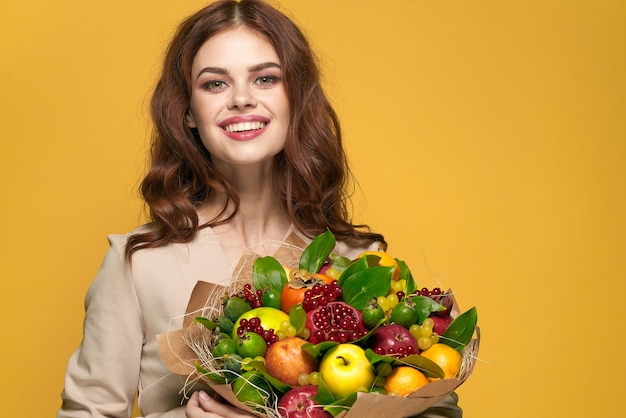 Sourire de jolie femme posant des émotions de bouquet de fruits frais fond isolé