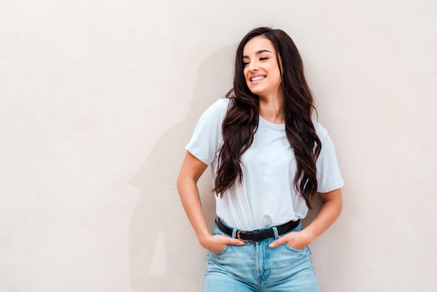 Sourire, jolie fille portant un t-shirt blanc et un jean posant. Place pour la publicité