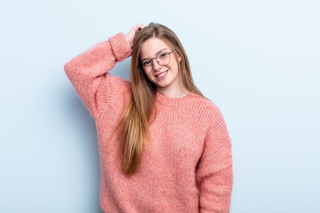 Sourire joyeusement et avec désinvolture en prenant la main à la tête avec un regard positif, heureux et confiant