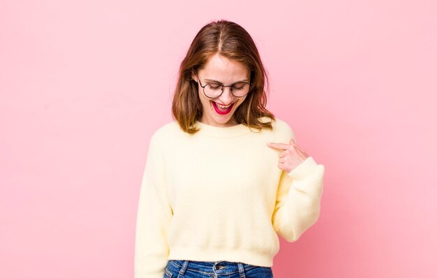 Sourire joyeusement et avec désinvolture en regardant vers le bas et en pointant vers la poitrine