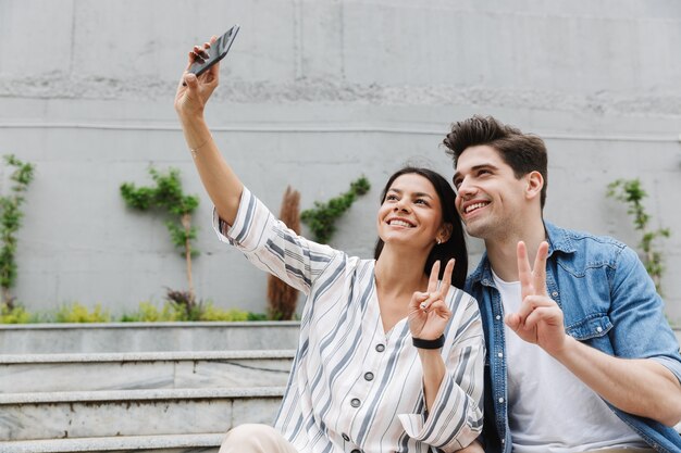 sourire joyeux jeune couple à l'extérieur prendre un selfie par téléphone mobile.