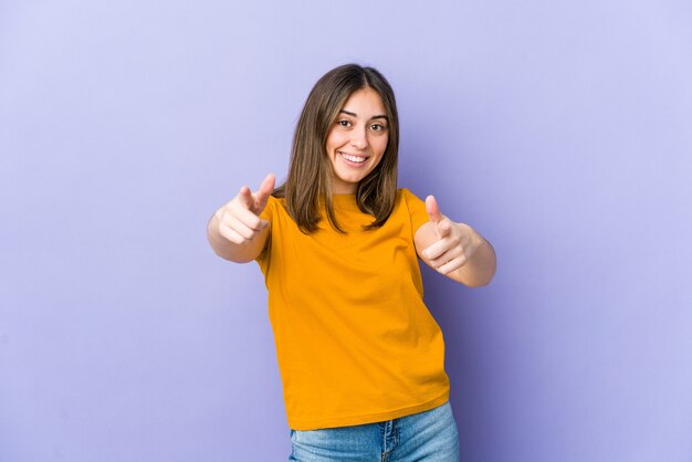 Sourire joyeux jeune femme caucasienne pointant vers l'avant.