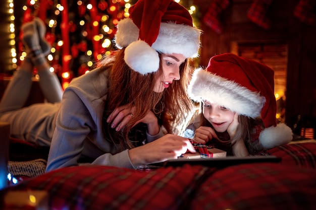 Sourire, mère, fille, santa, chapeaux, pyjamas, regarder, drôle, vidéos