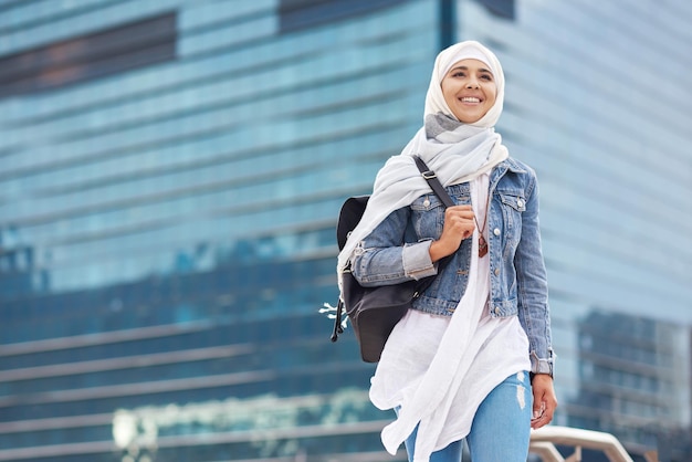 Sourire musulman et femme en ville pour un objectif de voyage et une future carrière sur fond de construction Bonne étudiante islamique et fille à New York pour un programme de stage ou une expérience avec une vision ou un état d'esprit