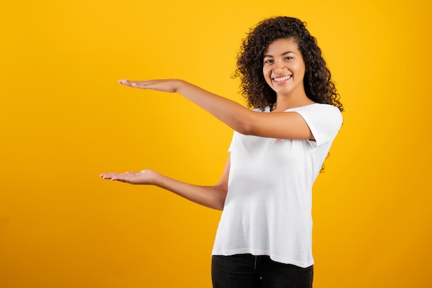 Sourire noir belle femme avec fond entre les mains isolées sur jaune