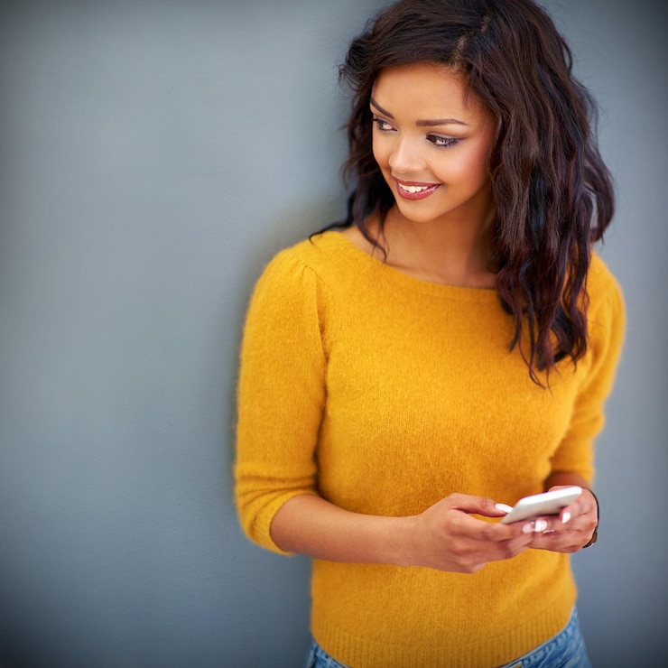 Photo sourire pensée et femme avec téléphone en studio pour les notifications des médias sociaux et la publication en ligne smartphone femme et heureuse avec la technologie pour le contact de message texte ou le chat sur fond gris