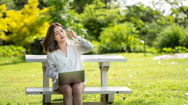 Sourire pensif femme dans le parc à l'aide d'une tablette numérique intelligente Portrait d'une jeune entreprise charmante