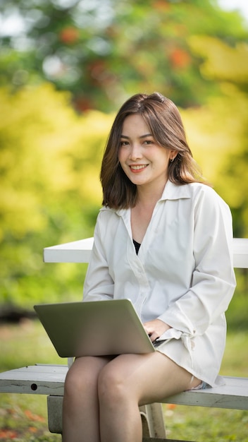 Sourire pensif femme dans le parc à l'aide d'une tablette numérique intelligente Portrait d'une jeune entreprise charmante
