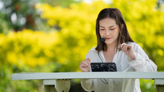 Sourire pensif Femme heureuse faisant des appels vidéo en ligne ou se rencontrant en ligne travaillant avec un ordinateur portable dans un parc