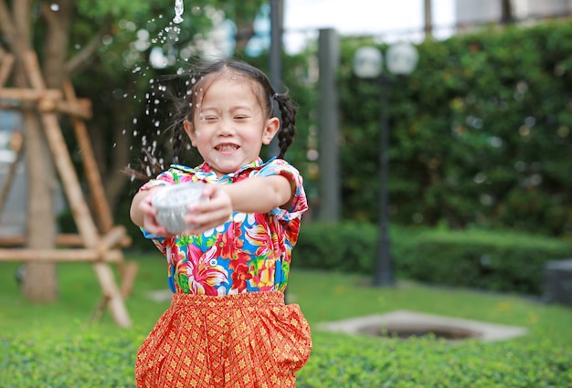Sourire de petits enfants thaïlandais asiatiques en robe d&#39;époque thaïlandaise éclaboussant de l&#39;eau au festival songkran