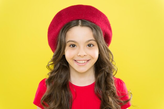 Un sourire sur ses lèvres Enfant souriant avec un sourire sain blanc sur un beau visage Adorable petite fille avec un grand sourire sur fond jaune Mignon petit enfant avec de longs cheveux ondulés et un sourire heureux