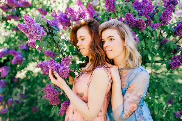 Sourire Des Soeurs Jumelles Joyeuses Dans Des Robes élégantes Posant Dans Le Parc D'été.