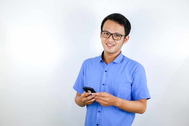 Sourire et visage heureux du jeune homme asiatique avec téléphone à la main Concept de modèle publicitaire avec chemise bleue