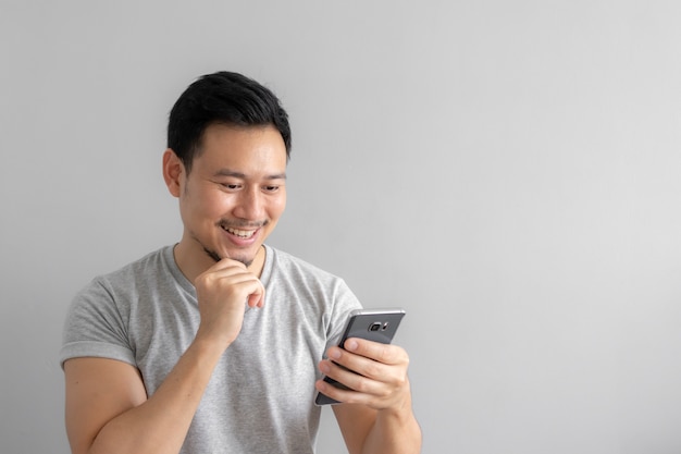 Sourire et visage heureux de l&#39;homme utilisent et touchent son smartphone.