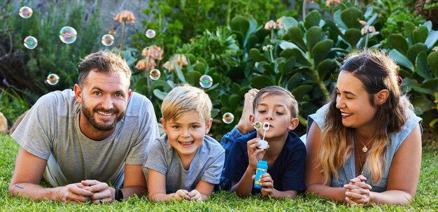 Sourires d'enfants cadeau de parentalité Portrait d'une belle famille allongée sur l'herbe et jouant avec des bulles dans un jardin