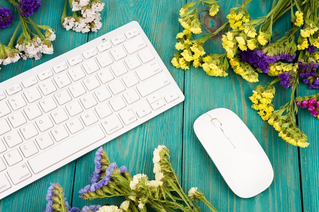 Souris clavier mince sans fil et fleurs colorées sur une table en bois bleue