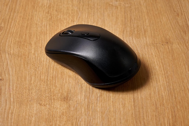 Une souris d'ordinateur noire sur une table en bois.