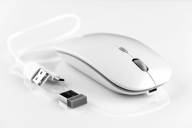 Souris d'ordinateur sans fil blanche à côté de l'adaptateur Wi-Fi et du câble de chargement