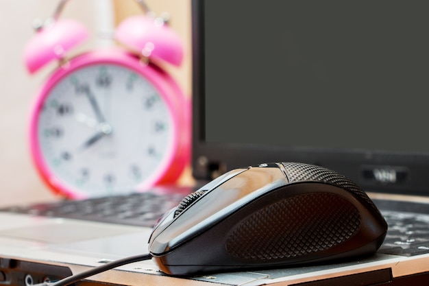 Souris près d'un ordinateur portable et d'une horloge