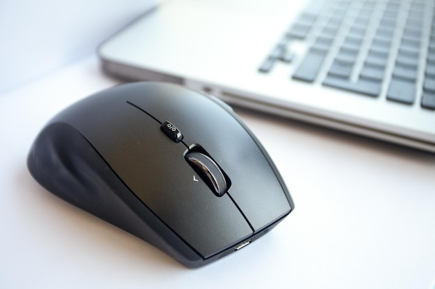 La souris sans fil est située près de l'ordinateur portable. Fond blanc, gros plan