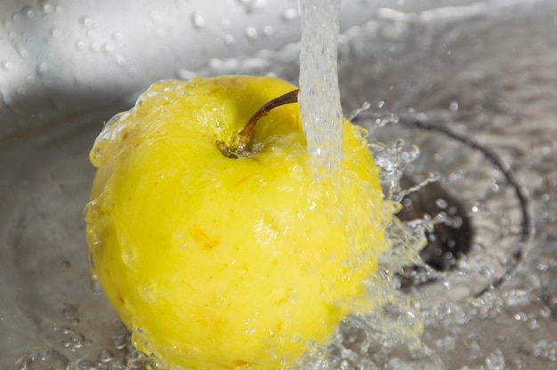 Sous le jet d'eau Apple jaune dans l'évier.