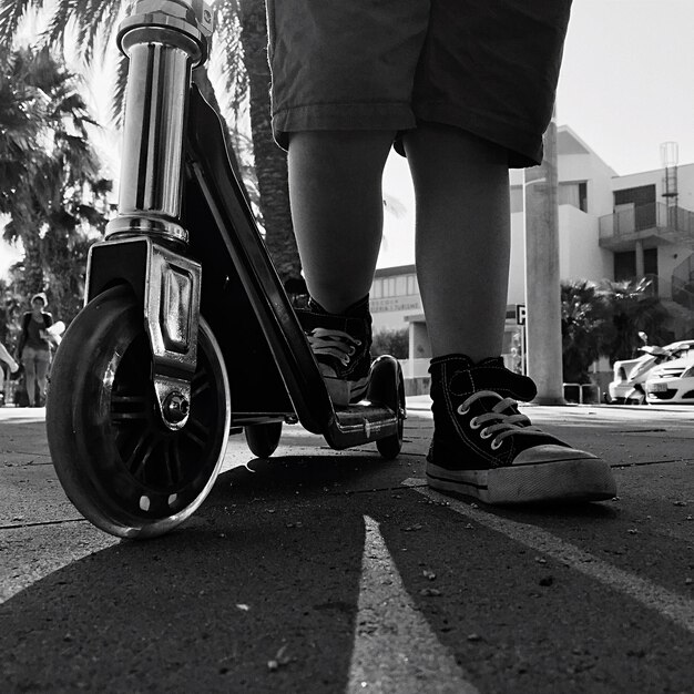 Photo sous-section d'un garçon avec un scooter de poussée debout sur la route