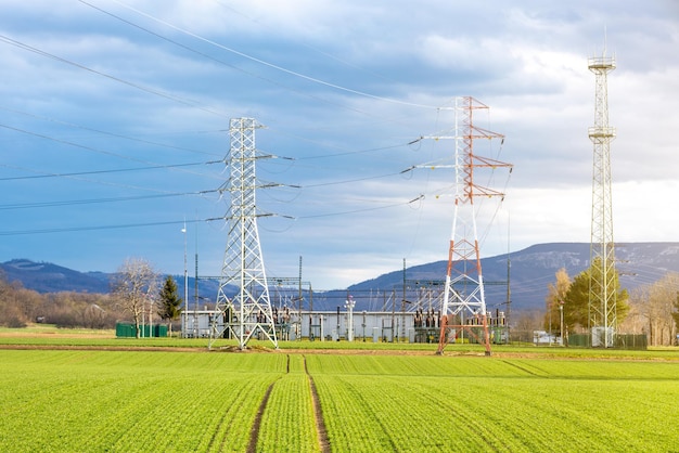 Sous-station de transformation sur un champ vert de nombreuses tours électriques