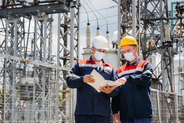 Les sous-stations électriques des ingénieurs effectuent une enquête sur les équipements modernes à haute tension dans le masque au moment de la pandémie. Énergie. Industrie.