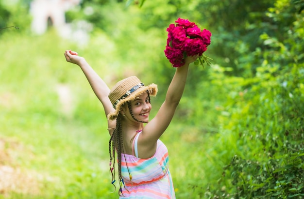 Sous le temps petite fille tenant un bouquet de fleurs en fleurs fraîches roses de composition de fleurs de roses Belle fille au chapeau de paille recueillir des roses enfance heureuse belle fille avec des fleurs