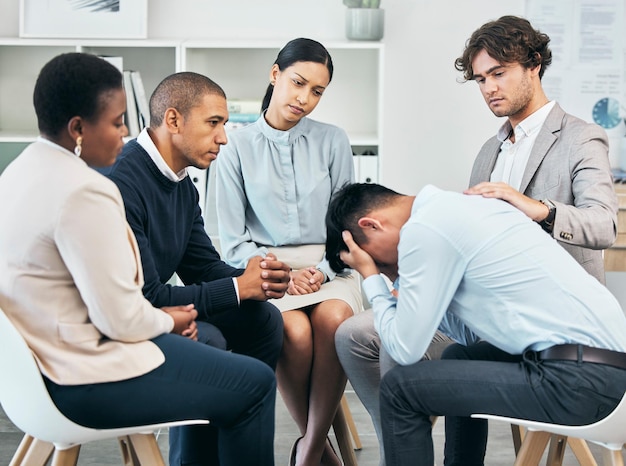 Soutien à la dépression et unité par des collègues réconfortant un homme après avoir reçu de mauvaises nouvelles au travail Soins communautaires de travailleurs assis ensemble pour soutenir leur ami après avoir été licencié ou par chagrin