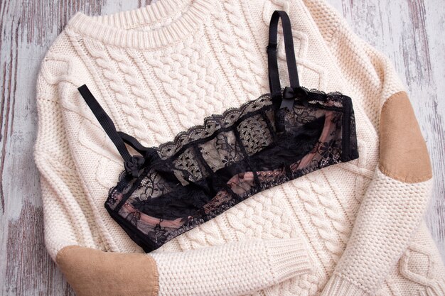 Soutien-gorge en dentelle noire sur un pull beige.