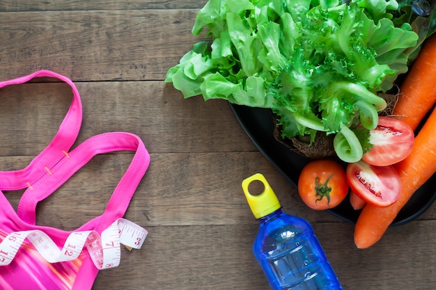 Soutien-gorge de sport de la femme et des aliments sains sur fond en bois