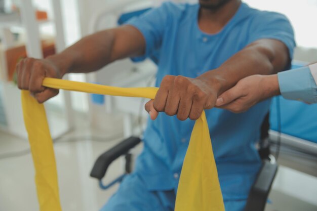 Photo soutien en physiothérapie bande d'étirement et infirmière avec un homme âgé pour la réadaptation en physiothérapie et l'aide aux soins de santé femme noire chiropraticien ou médecin en physiothérapie consultant un patient âgé