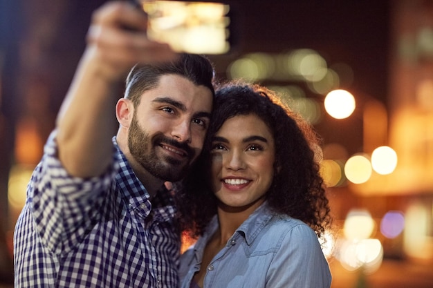 Des souvenirs sont faits de cette photo d'un jeune couple affectueux prenant un selfie lors d'un rendez-vous en ville