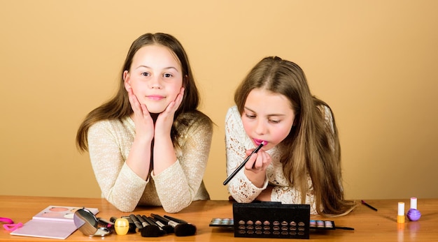 Soyez créatif avec la collection de maquillage. Petits maquilleurs au travail. Petites filles mignonnes se maquillant sur la peau du visage. Adorables enfants peignant le visage avec un pinceau de maquillage.