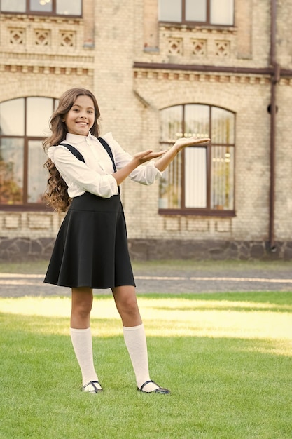 Soyez ma fashionista présentant les avantages de l'éducation moderne enfant élève à la cour d'école enfant à la pause scolaire mode et beauté fille a les cheveux bouclés petite fille porte un uniforme chic de retour à l'école